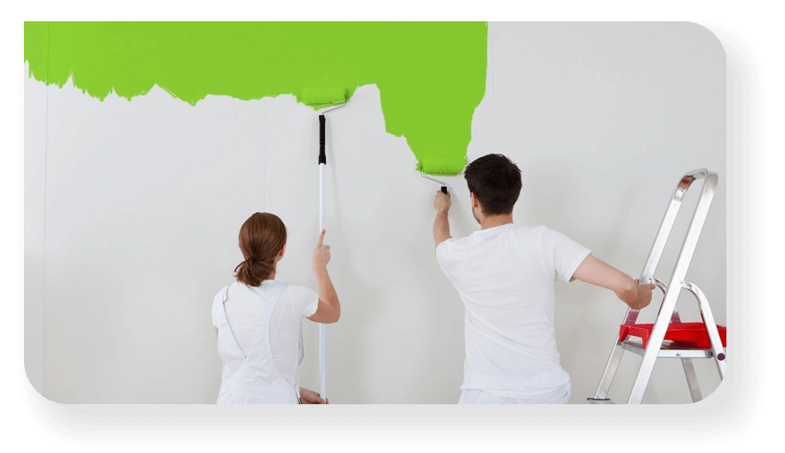 A couple wearing white painting a green wall